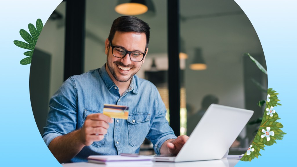 Man smiling as he enters card details to complete an online transaction