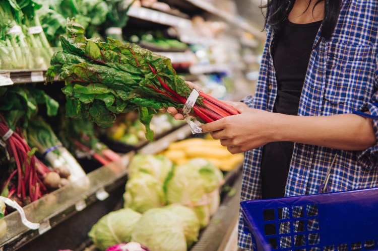 person buying chard in the grocery store