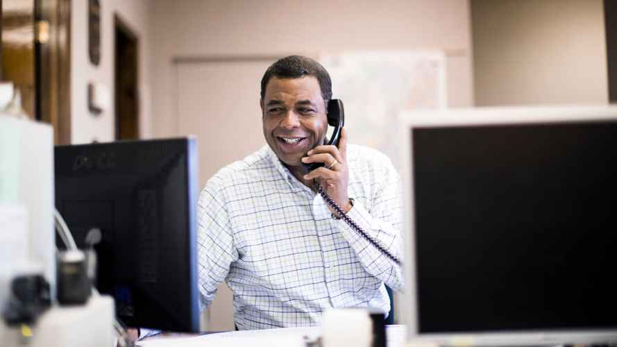 person on the phone at a desk in front of a computer