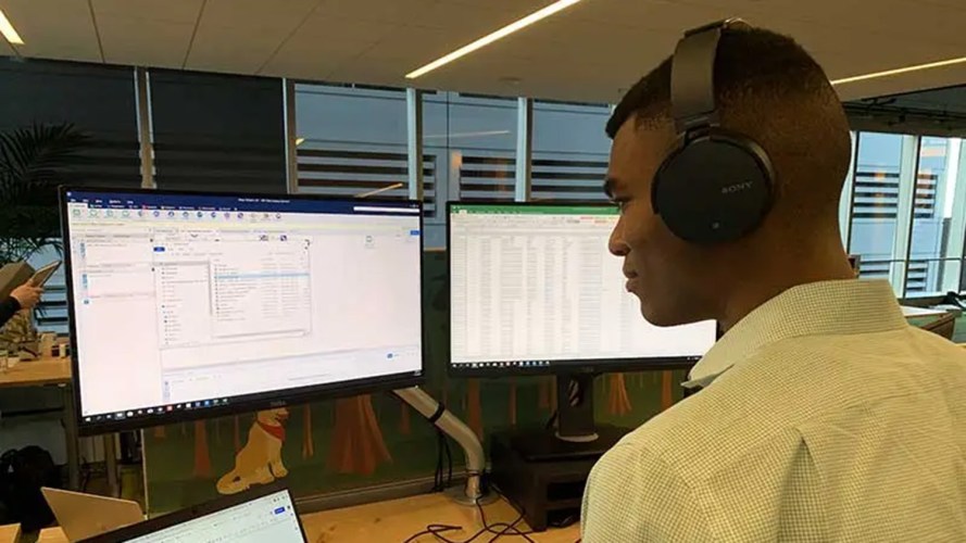 A man with headphones on, sitting and working on a laptop at a desk