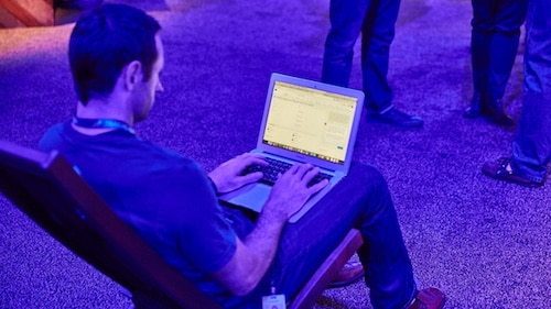 Photo of a man with a laptop in conversation with a bot