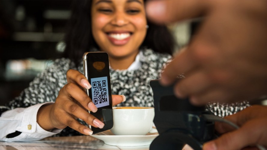 Woman showing QR code on her mobile phone to a merchant.