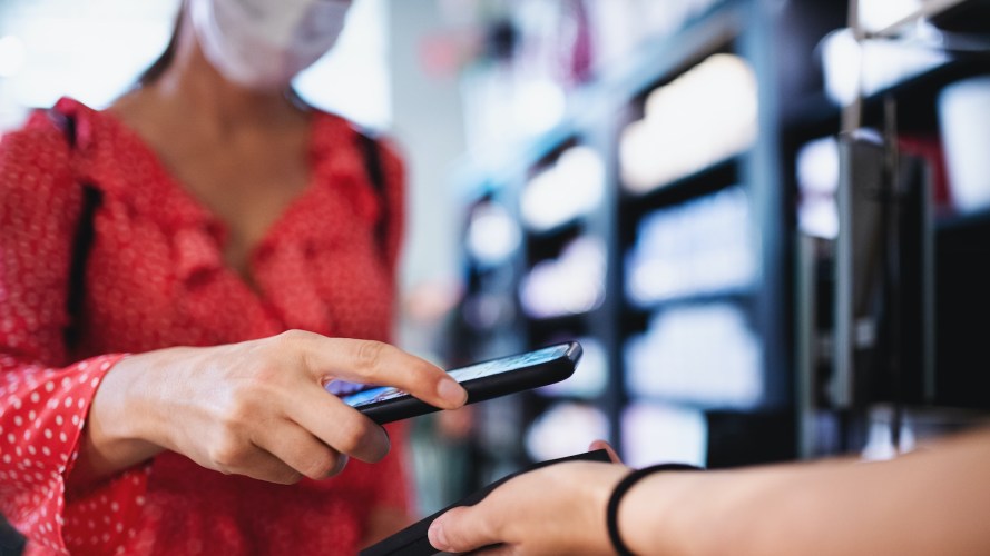 Woman wearing face mask pays with a mobile device