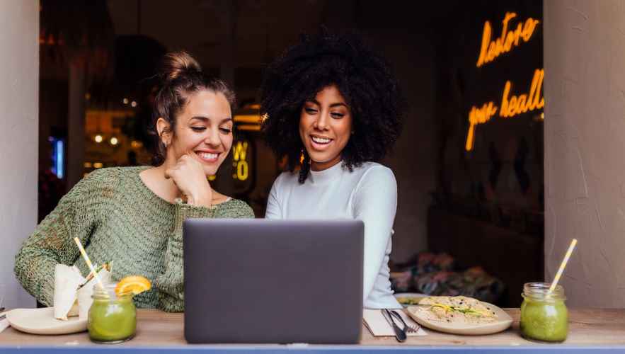 Two women shopping online in a cafe