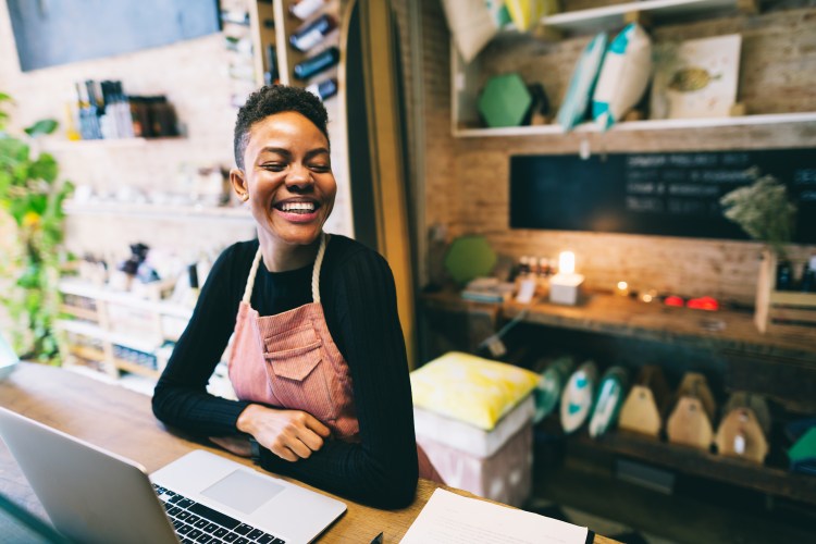Female small and medium business owner smiling at her shop trends report