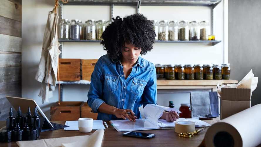 A woman working in a shop looks through some paperwork