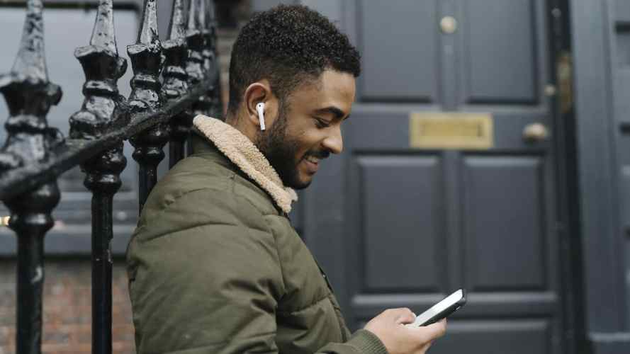 smiling person with earbuds and a phone