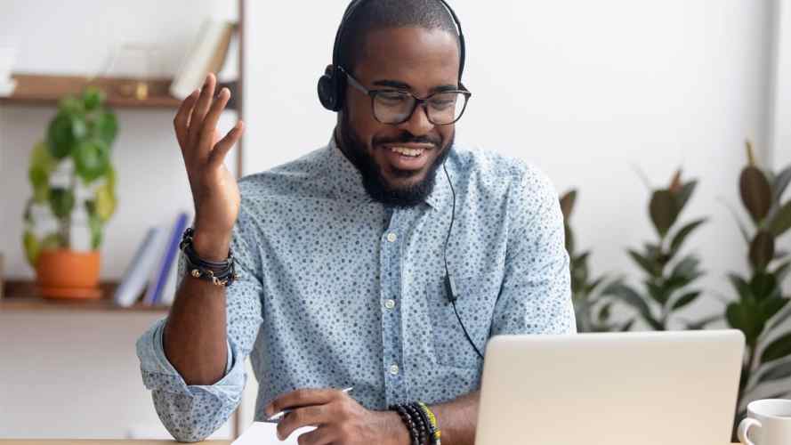 smiling person on a headset using a laptop computer