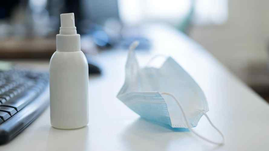 Hand sanitizer and face mask on a worker's desk office safety small business