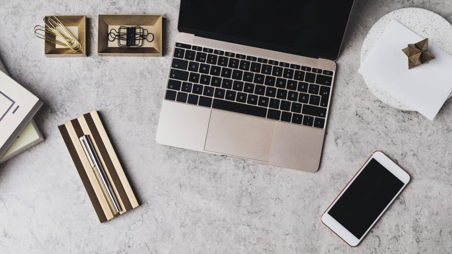 a desk with a laptop, pen, and binder clips