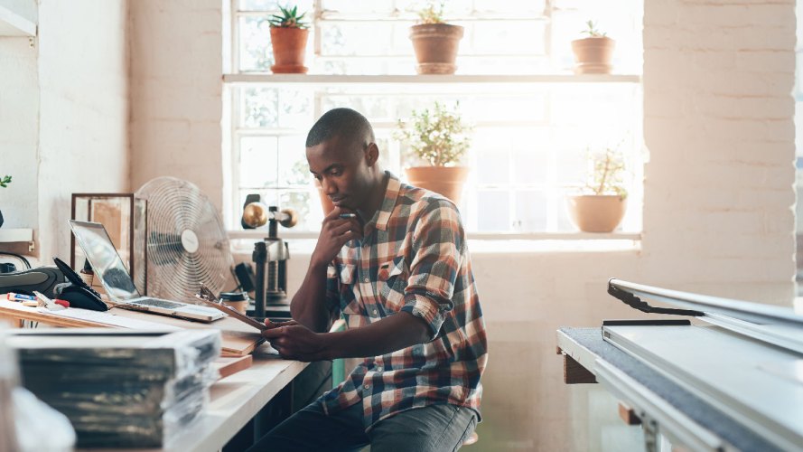 man at table on mobile phone, materials around him, small business rebound