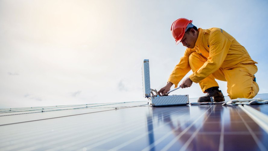 man servicing solar panels manufacturing sustainability