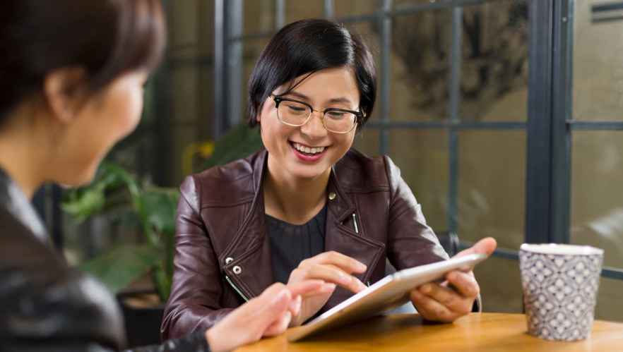 Two women using a tablet in a coffee shop