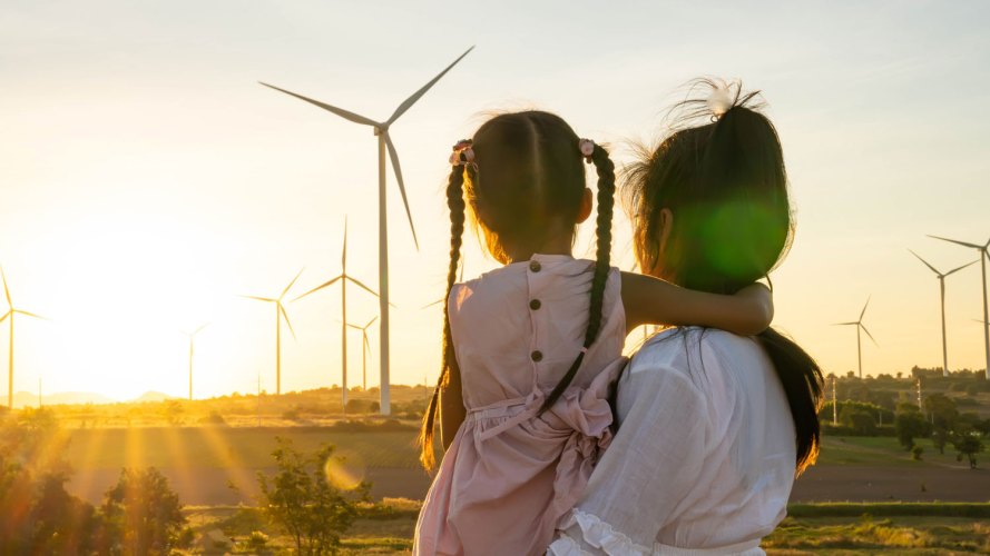 backs of woman and child as they look at wind turbines energy economy utilities, E&U