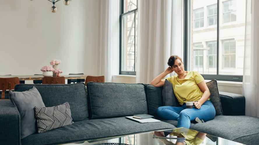 Woman sitting on a couch at home with notebook and laptop closed