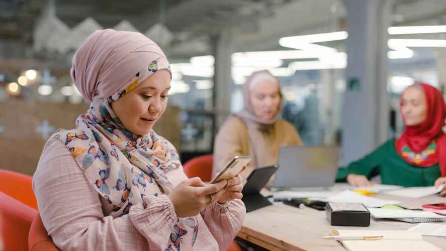 Three women working in an office on laptop and phone