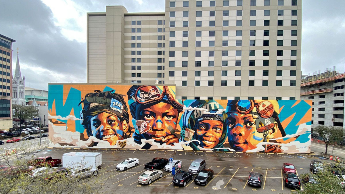 Four close-up faces of children on a colorful mural on a wall in parking lot in Houston, Texas.