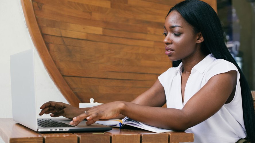 professional woman in a casual environment, working on her laptop. Marketers grow with Slack marketing workflows.