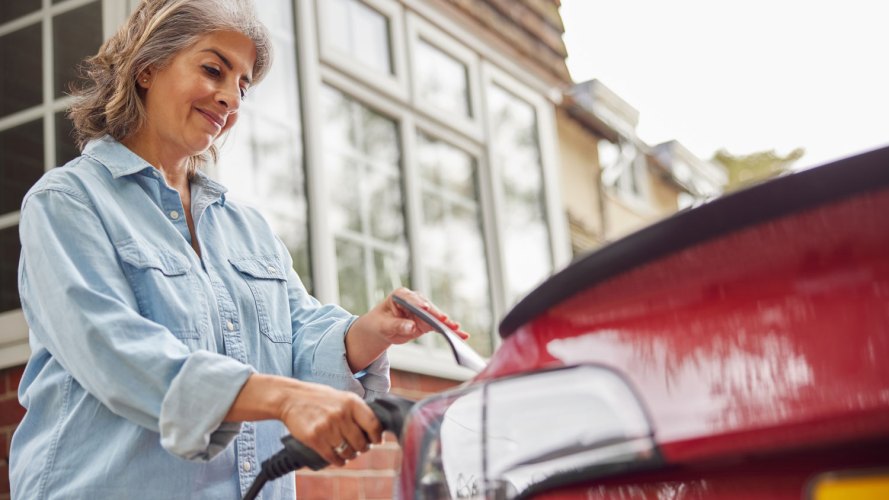 woman attaching her electric vehicle to a charging cable.