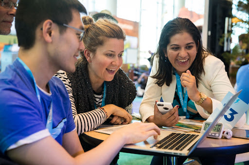 3 colleagues gathered around a laptop for a collaborative Trailhead trail gamification