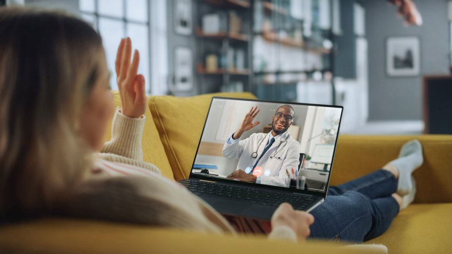 woman sitting on a sofa waving to her doctor on a telemedicine call network providers management