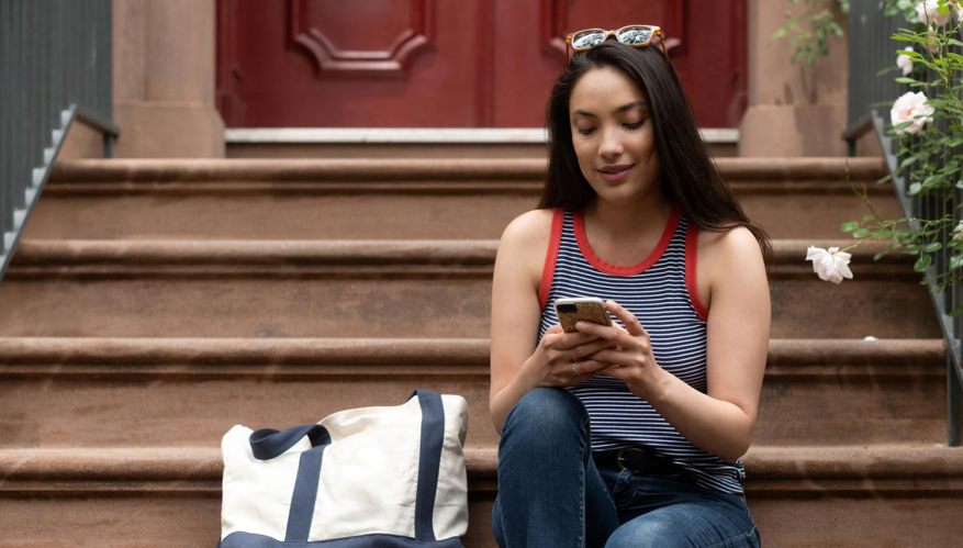 A photo of a woman looking at her phone. Loyalty programs.