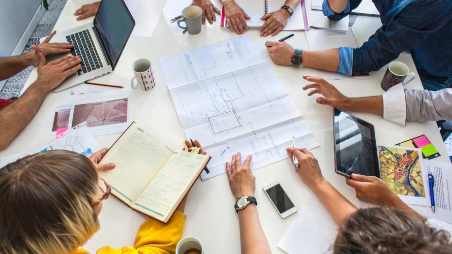 people collaborating and gathered around a table with notebooks and smartphones on the table