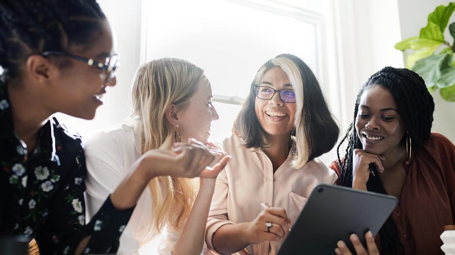 four women colleagues meeting and looking at a tablet: government employee experience