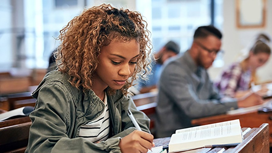 A student taking notes at a desk in class