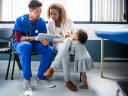 male healthcare professional sitting with a mother and child looking at files