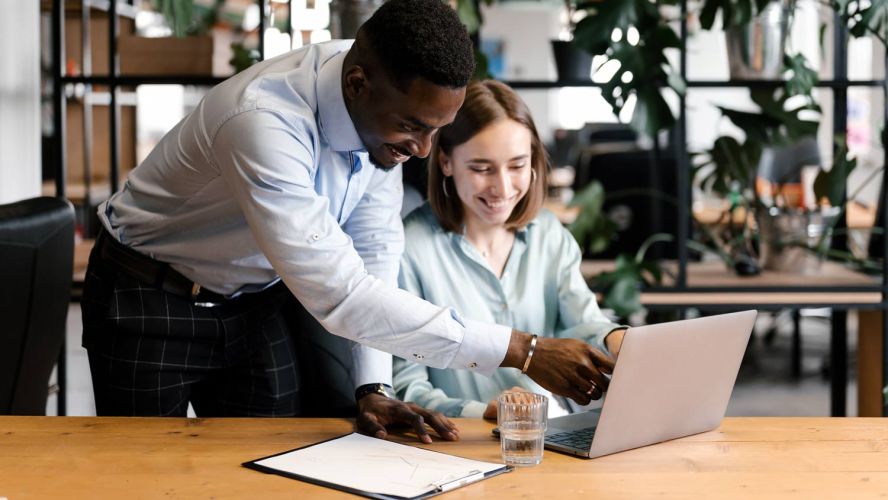 Two people at work looking at a laptop, perhaps at marketing data analytics.