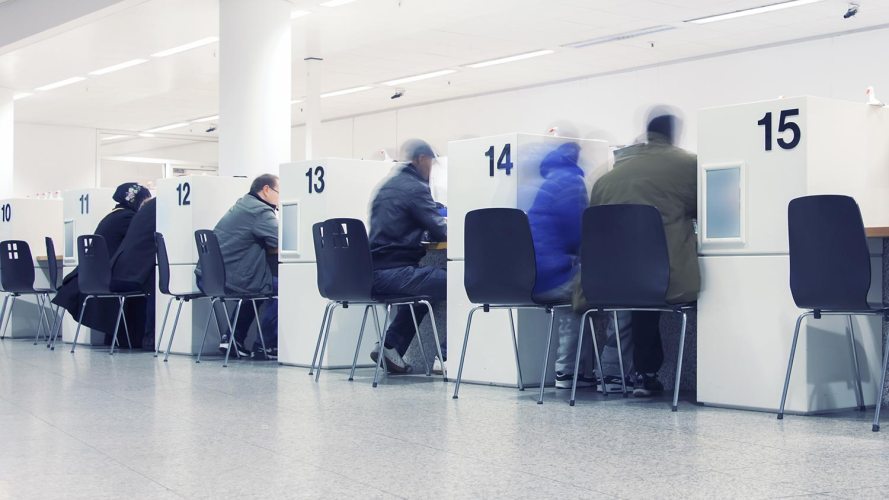 Open office of a public sector, government building where citizens are in chairs, interacting with unseen employees: zero trust architecture