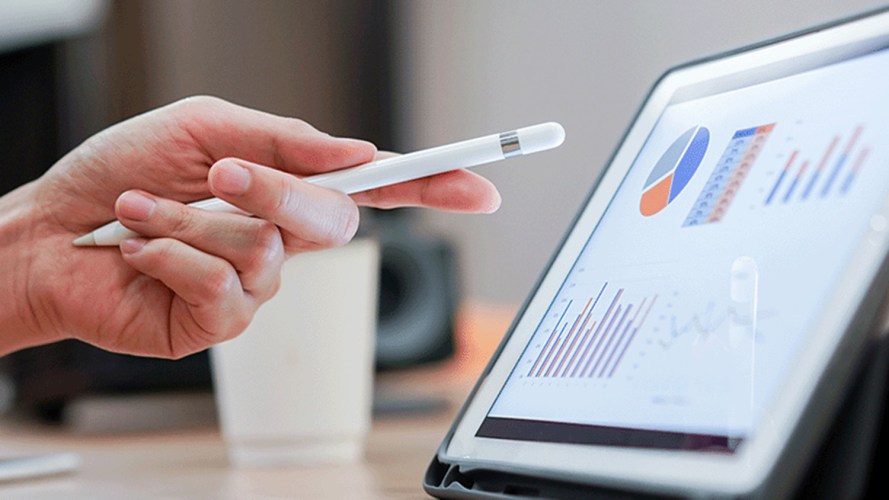 Hand holding a pen, pointing at a tablet with Tableau