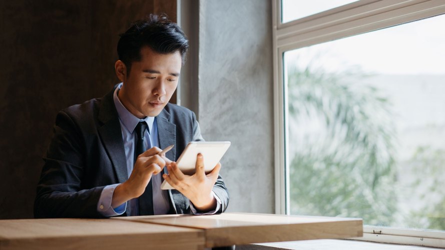 Man in suit looking at his smart tablet: insurance brokerage agency predictive analytics