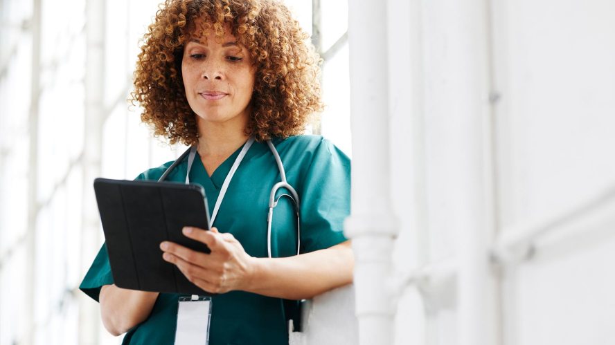 A woman in scrubs looks at a tablet. Healthcare ecommerce