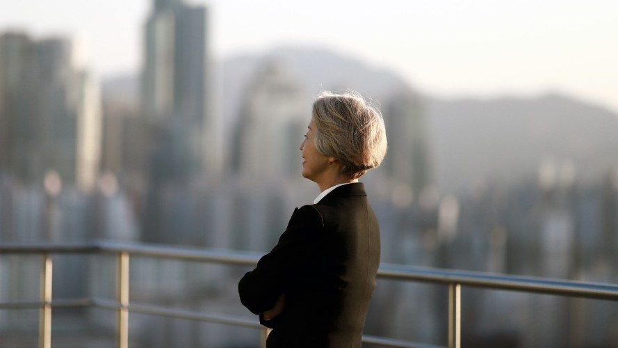 A business woman looking out over an outside city view. Corporate leaders.