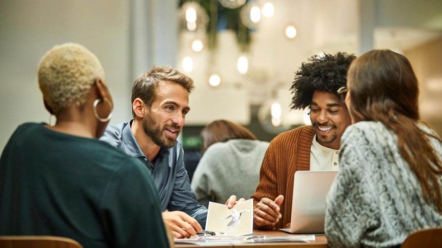 Four people sit at a table discussing work, a possible impact of automation.