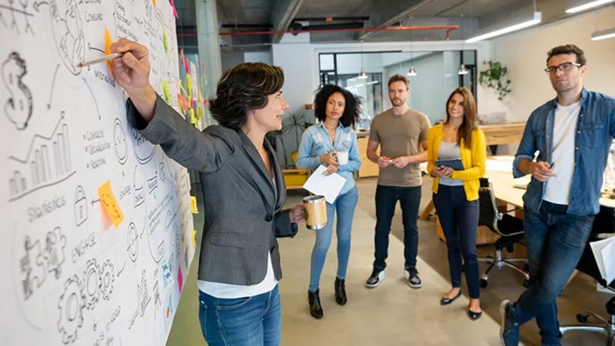 A group of four people standing at looking at a board