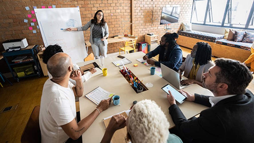 Woman presenting to a group of colleagues sitting at a table