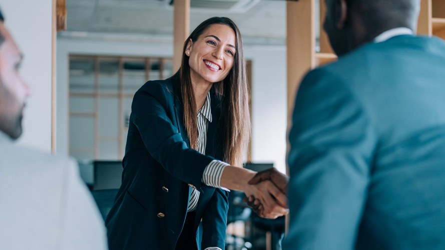 A businesswoman greets Salesforce partners in a meeting.