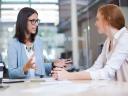 Working to improve the financial advisor-client relationship, a businesswoman speaks with her client in an office setting