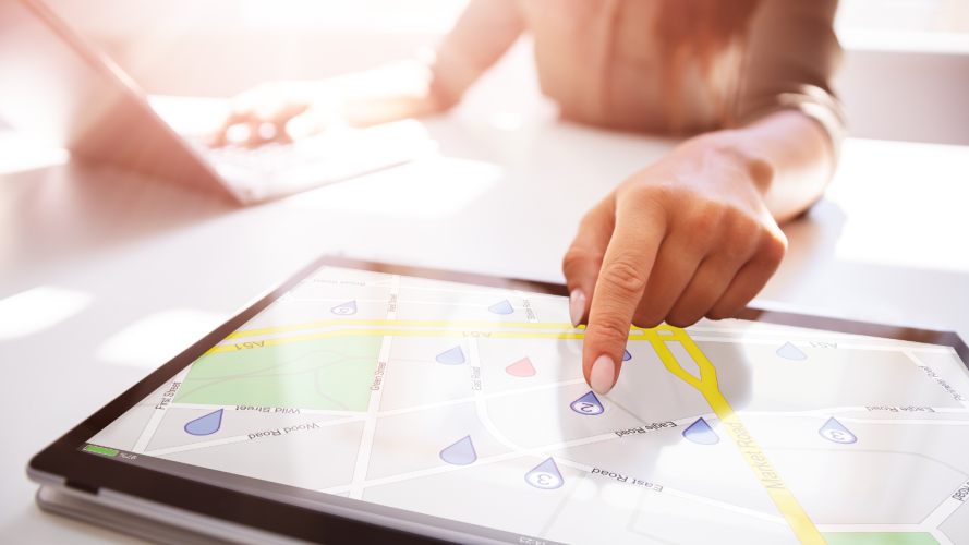 A person using index finger to point to a marker on a digital map on a tablet.