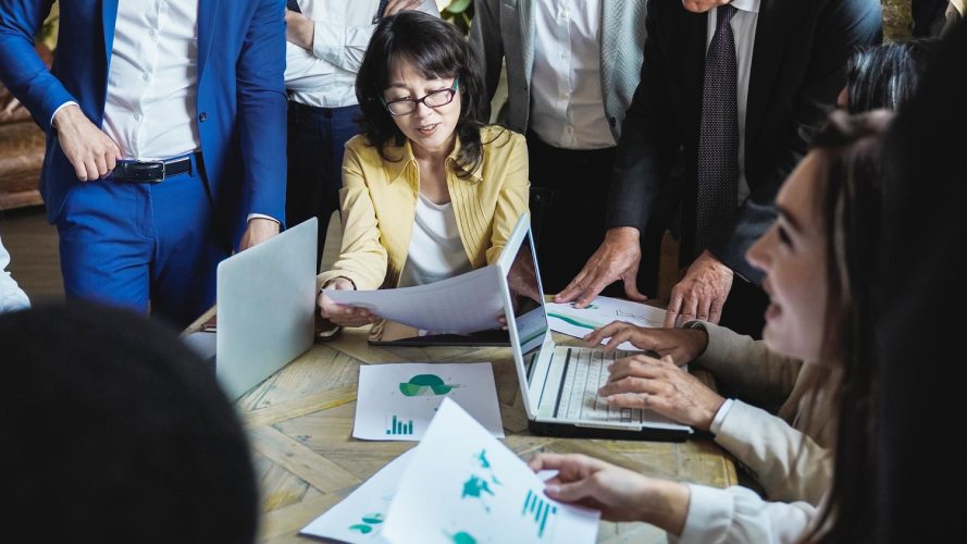 Businesswoman in yellow jacket leading a corporate team in an office setting, developing an ESG reporting strategy