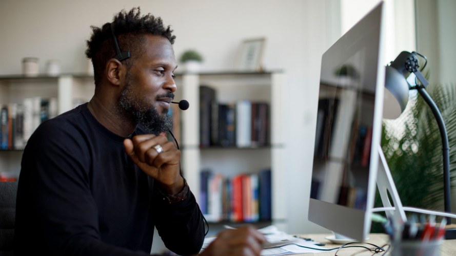 Businessman in a remote office, wearing a headset at a desktop computer / communications industry ESG