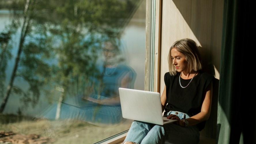 Woman sitting in her house by the lake, looking at her laptop / what is a data lakehouse