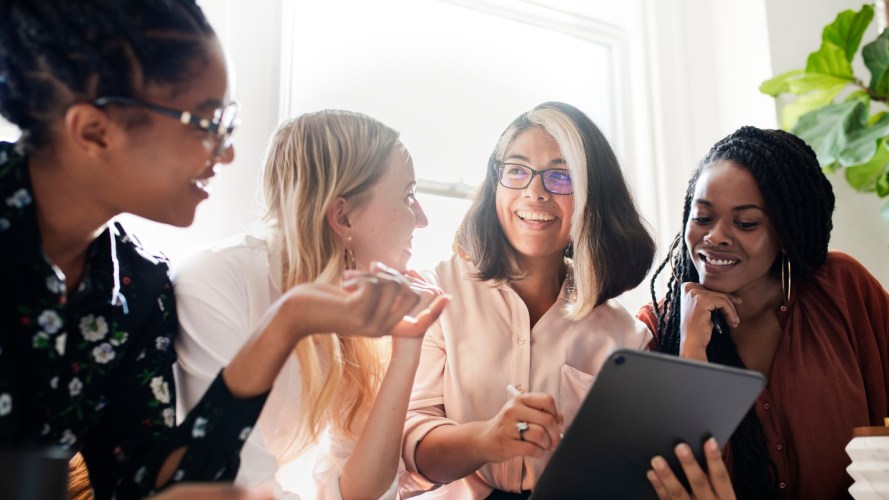 A group of women having a business meeting and holding technology.