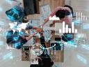 Four people sit at a table and encourage teamwork to focus on AI innovation with data and graphs overlaid.