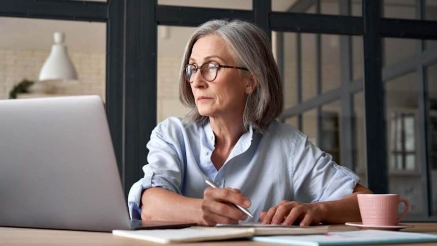 Female chief revenue officer looking at a laptop while writing something down