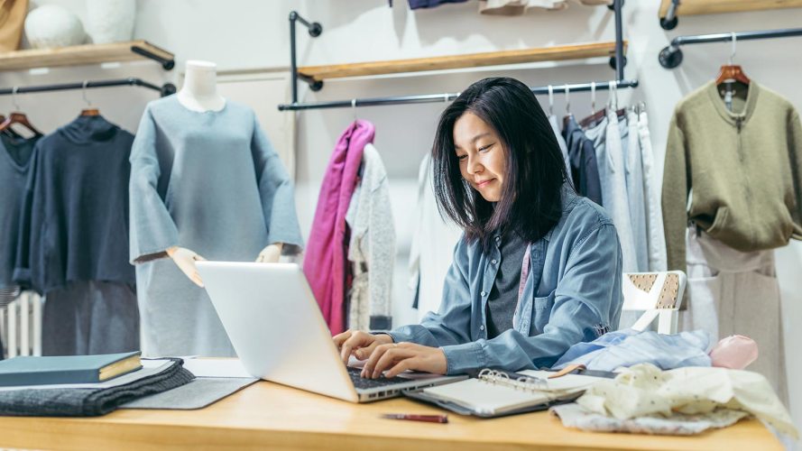 A retail employee works on a laptop in front of a merchandise display: retail execution solutions