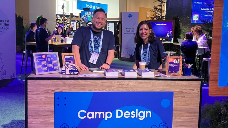Two Salesforce employees smiling at the Camp Design welcome desk.